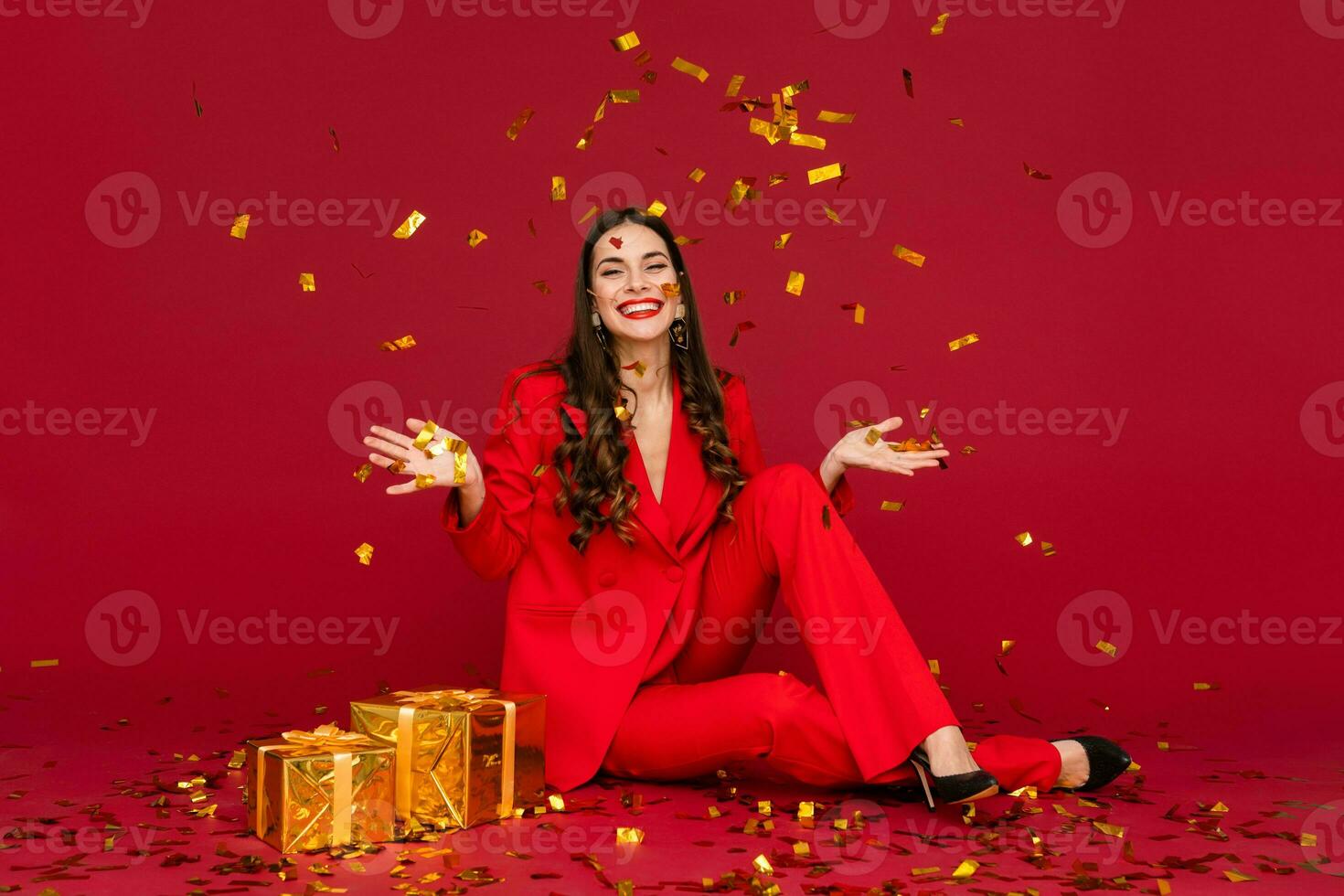 attractive woman celebrating Christmas on red background in confetti photo