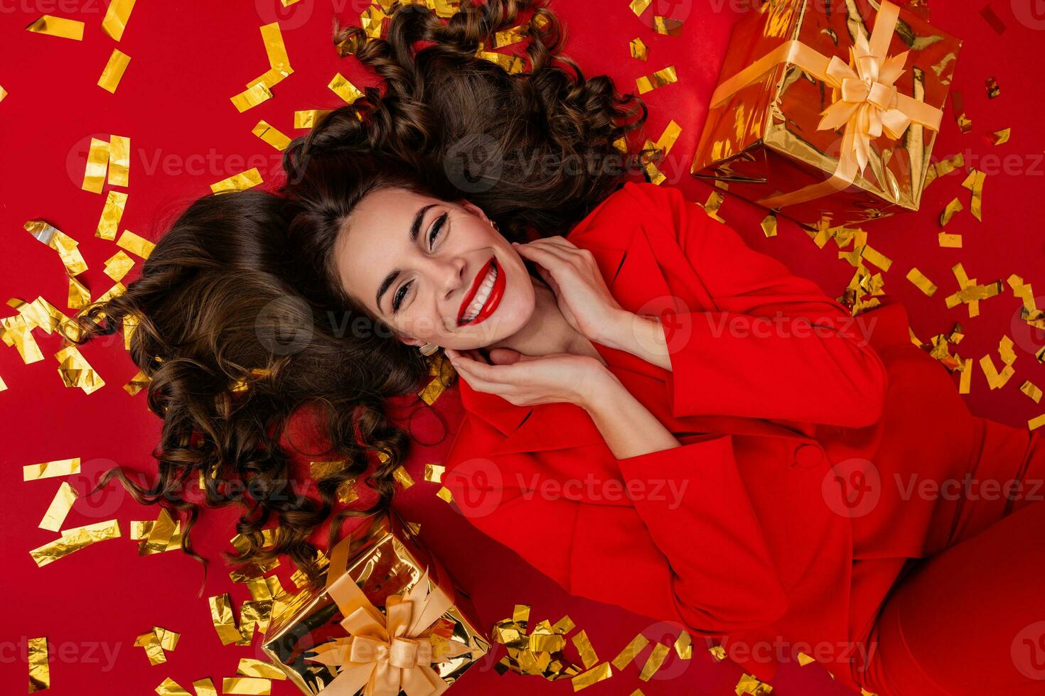 attractive woman celebrating Christmas on red background in confetti photo