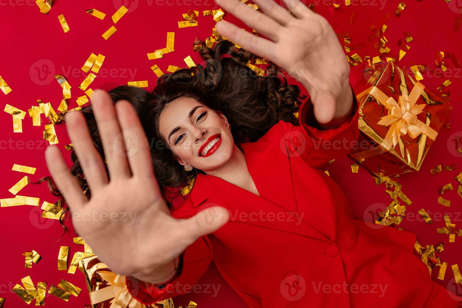 attractive woman celebrating Christmas on red background in confetti photo