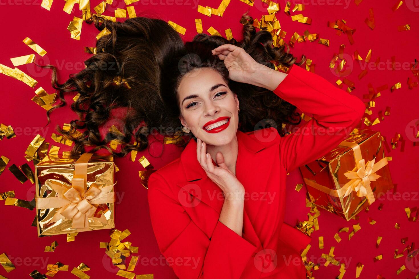 attractive woman celebrating Christmas on red background in confetti photo