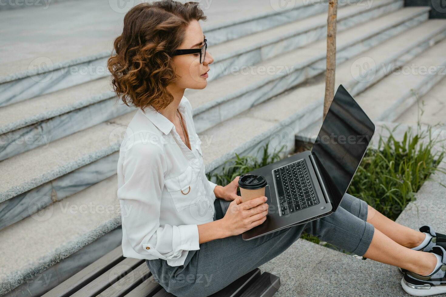 attractive business woman working outside on laptop photo