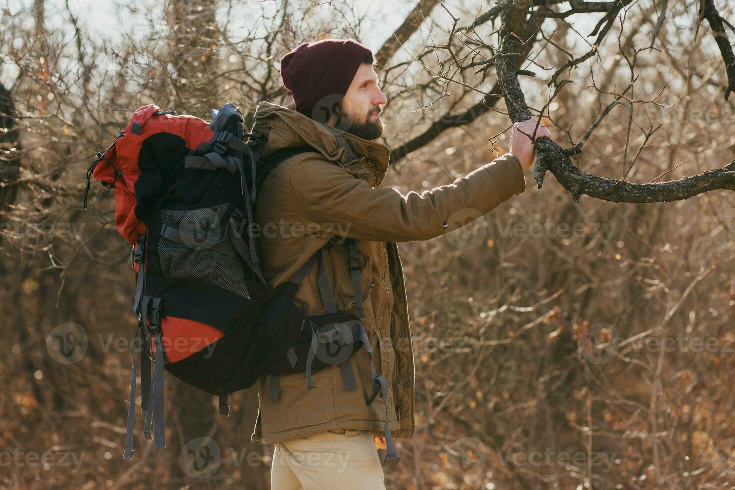 young hipster man traveling with backpack in spring autumn forest photo