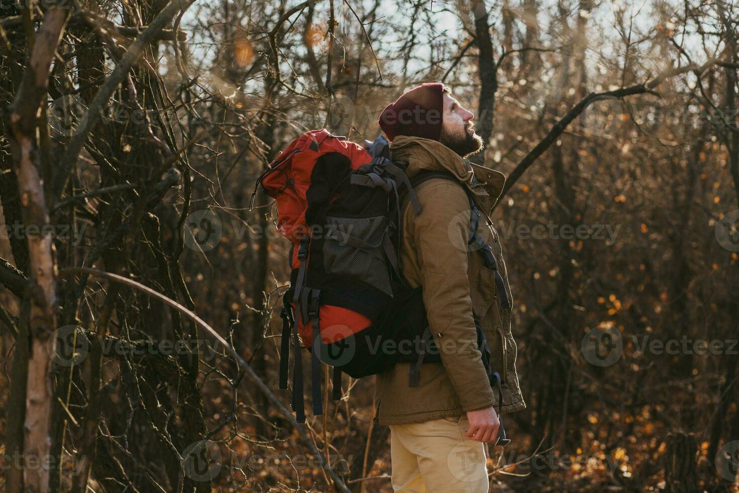 young hipster man traveling with backpack in spring autumn forest photo