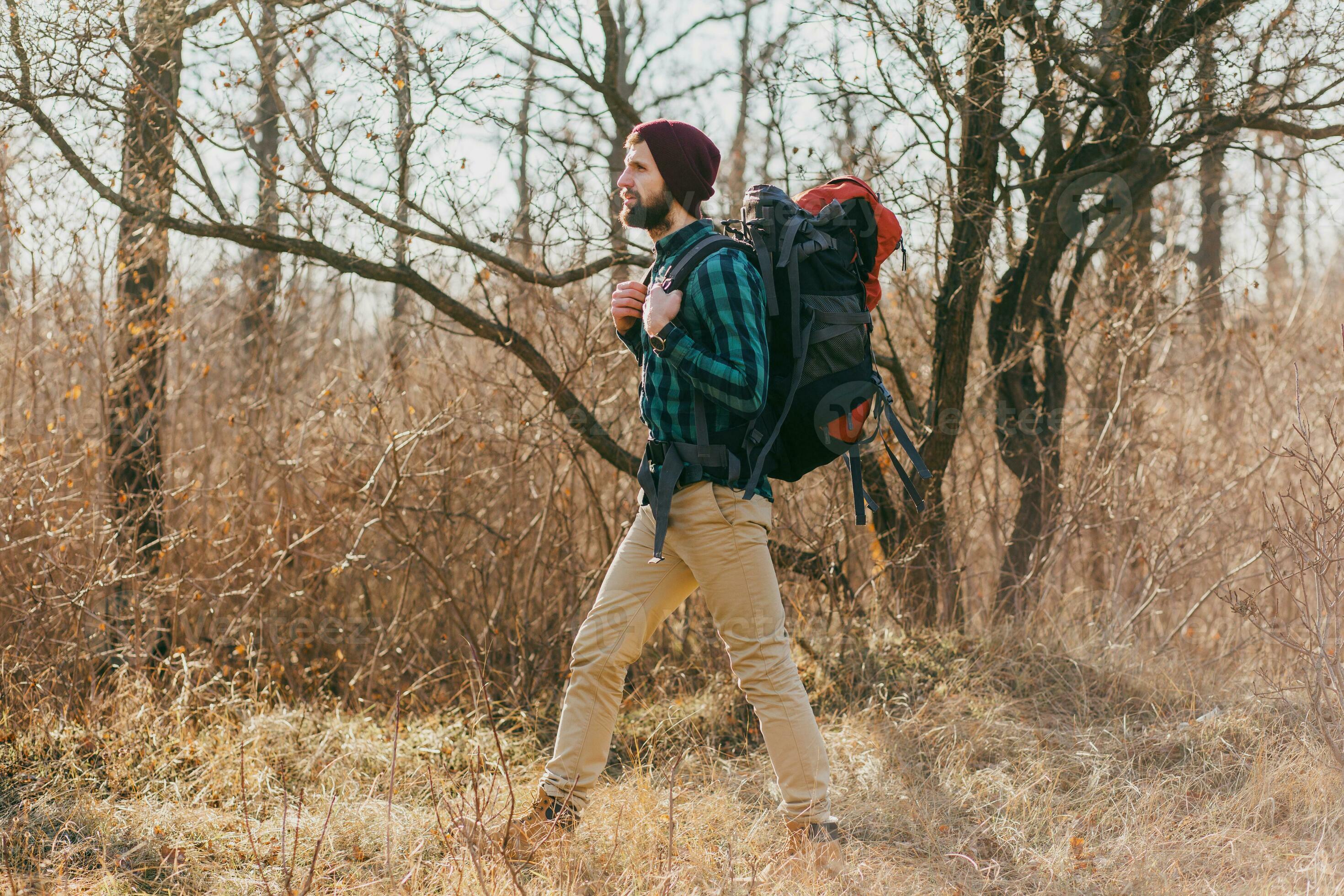 Hipster man with backpack exploring nature in spring, walking