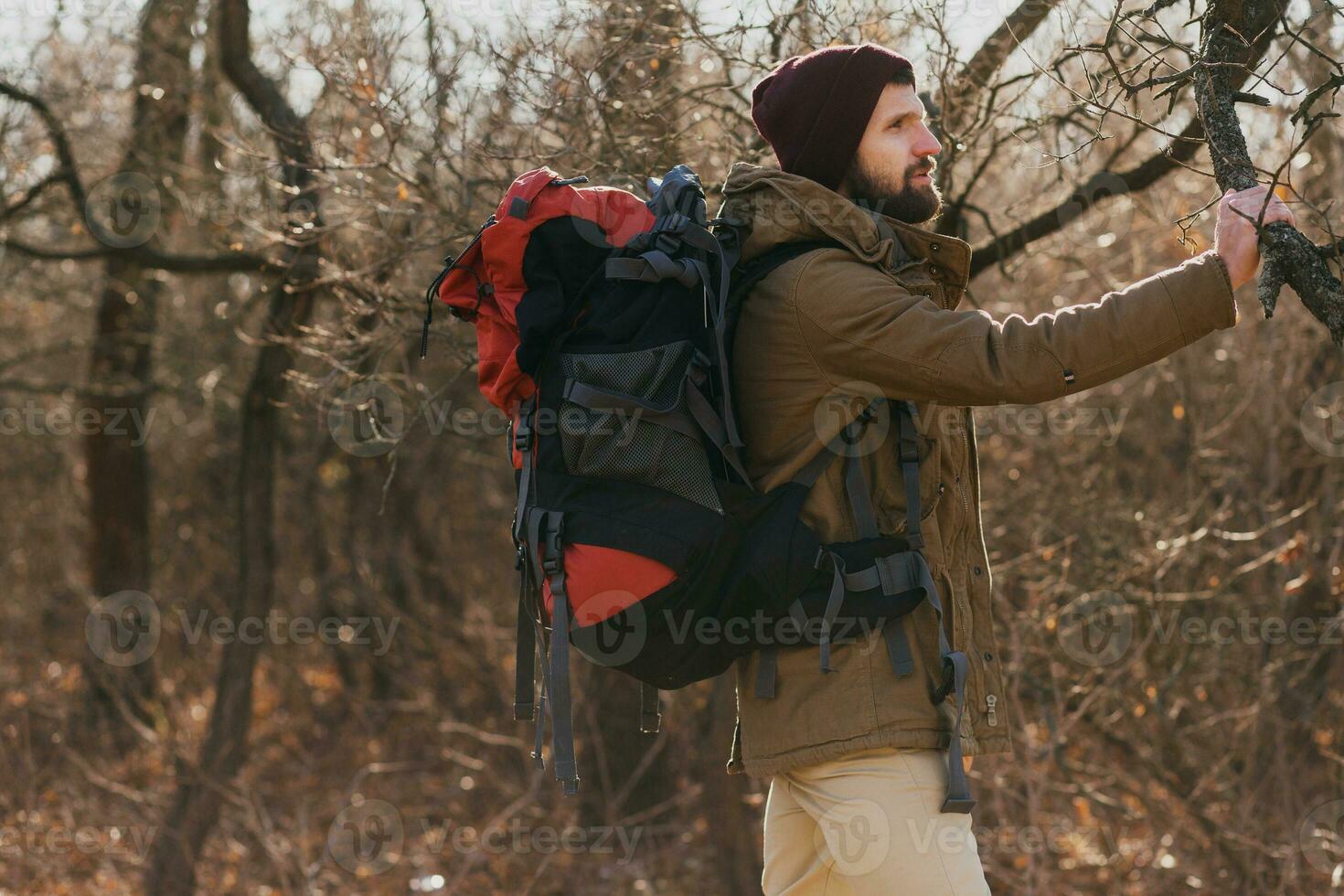 young hipster man traveling with backpack in spring autumn forest photo