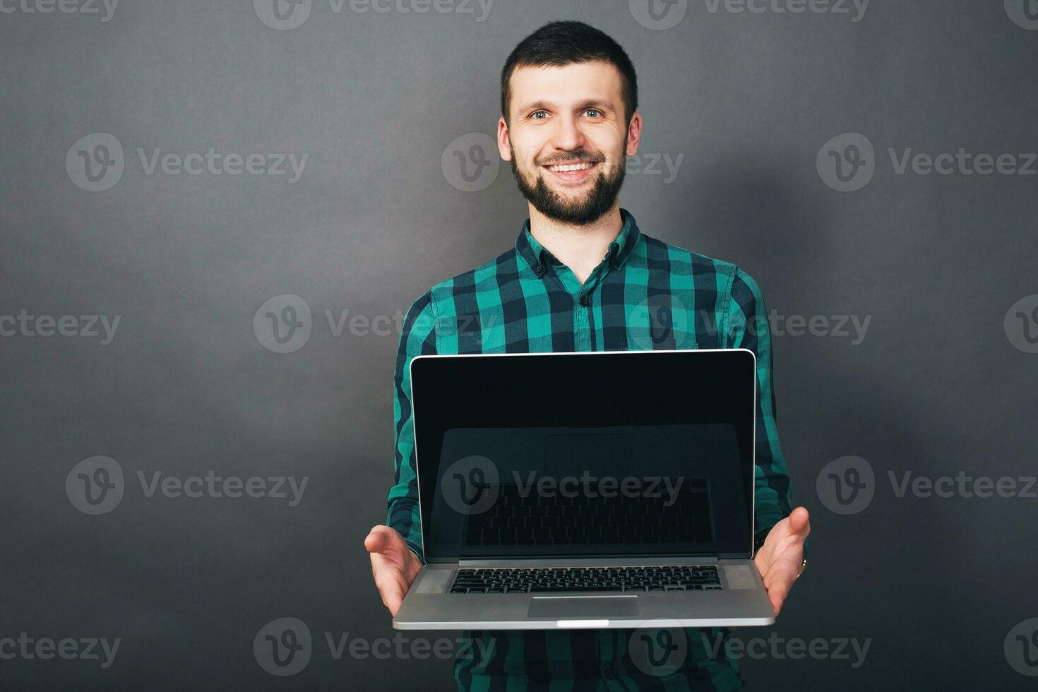 joven hermoso hipster barbado hombre en gris fondo, verde a cuadros camisa foto