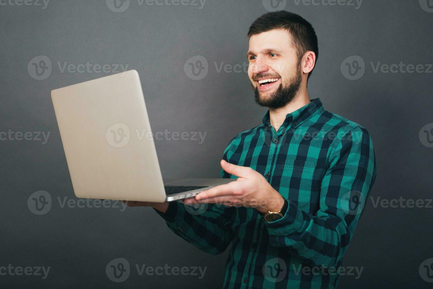 young handsome hipster bearded man on grey background, green checkered shirt photo