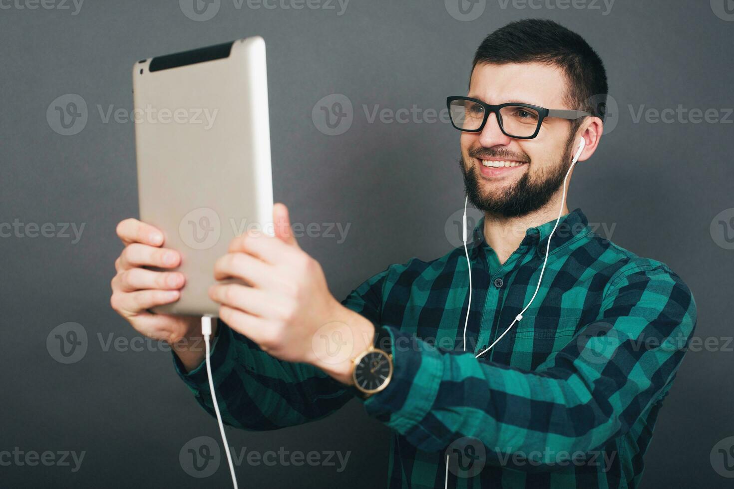 young handsome hipster bearded man on grey background, green checkered shirt photo