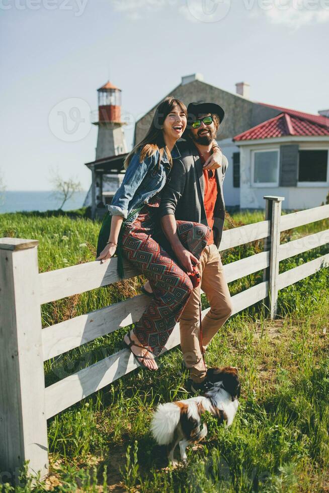 young stylish hipster couple in love walking with dog in countryside, having fun photo