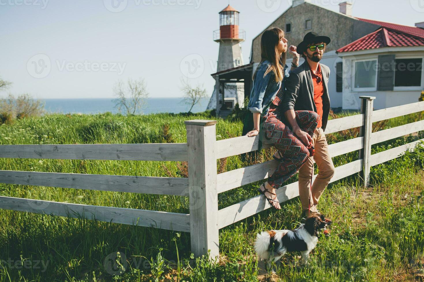 young stylish hipster couple in love walking with dog in countryside, having fun photo