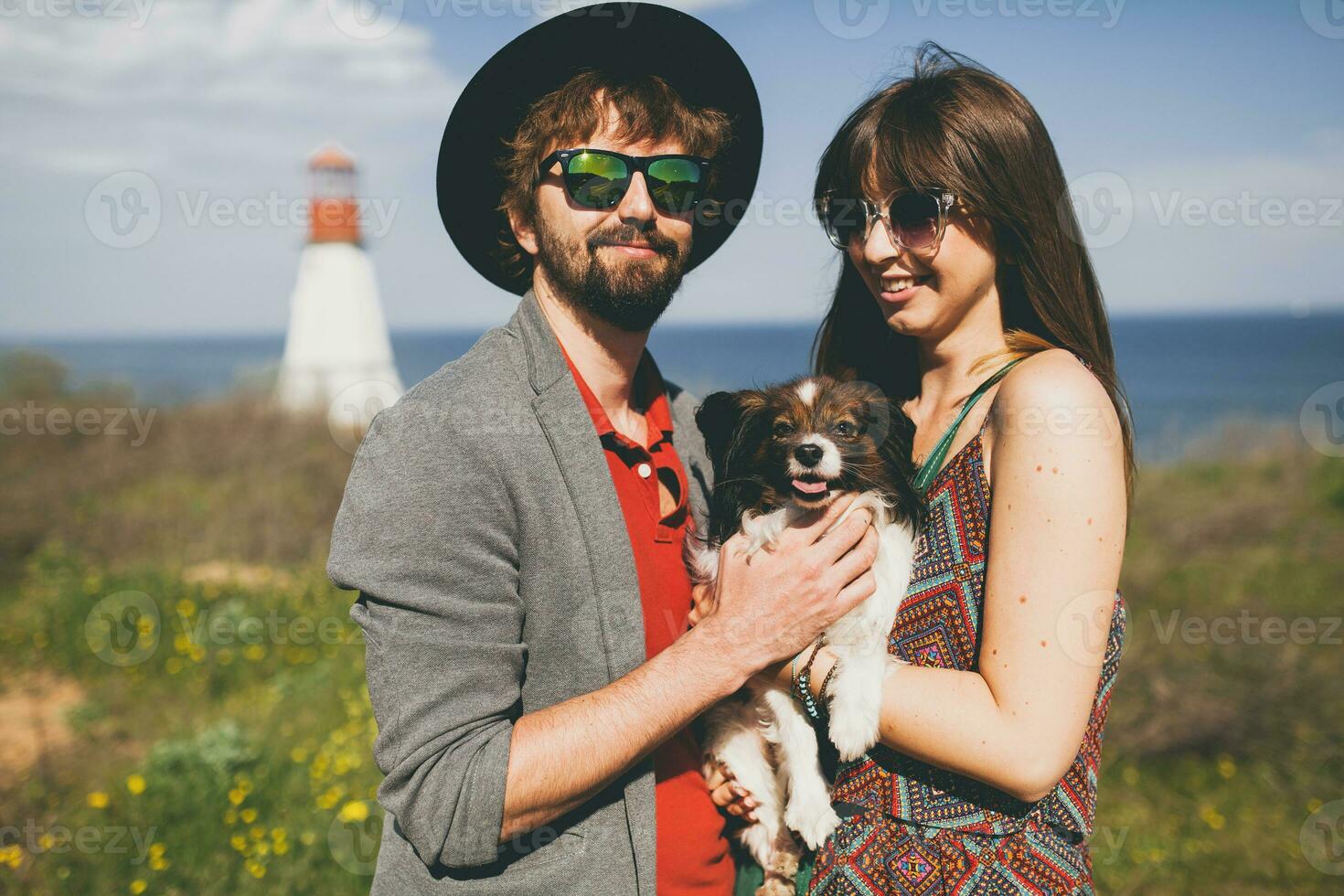 happy young stylish hipster couple in love walking with dog in countryside photo