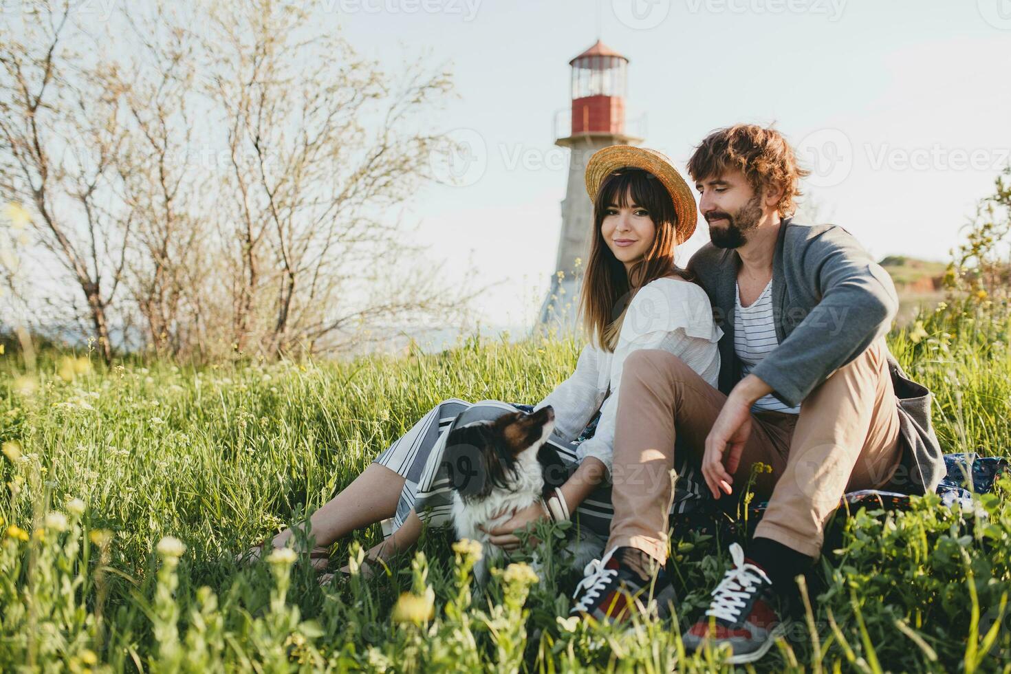young stylish hipster couple in love walking with dog in countryside, having fun photo