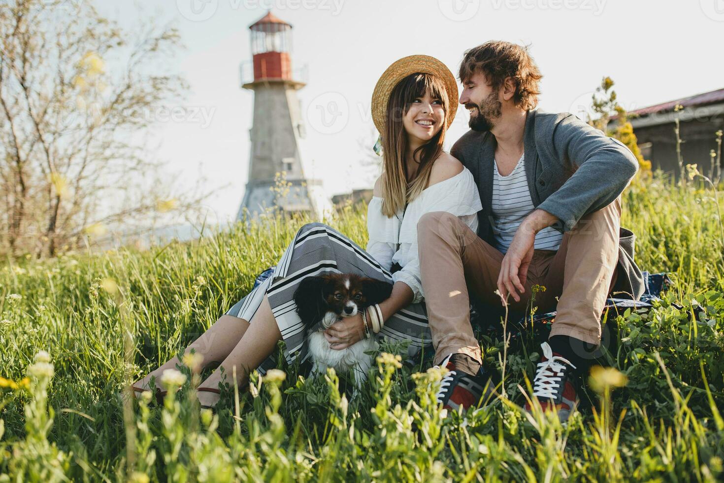 young stylish hipster couple in love walking with dog in countryside, having fun photo