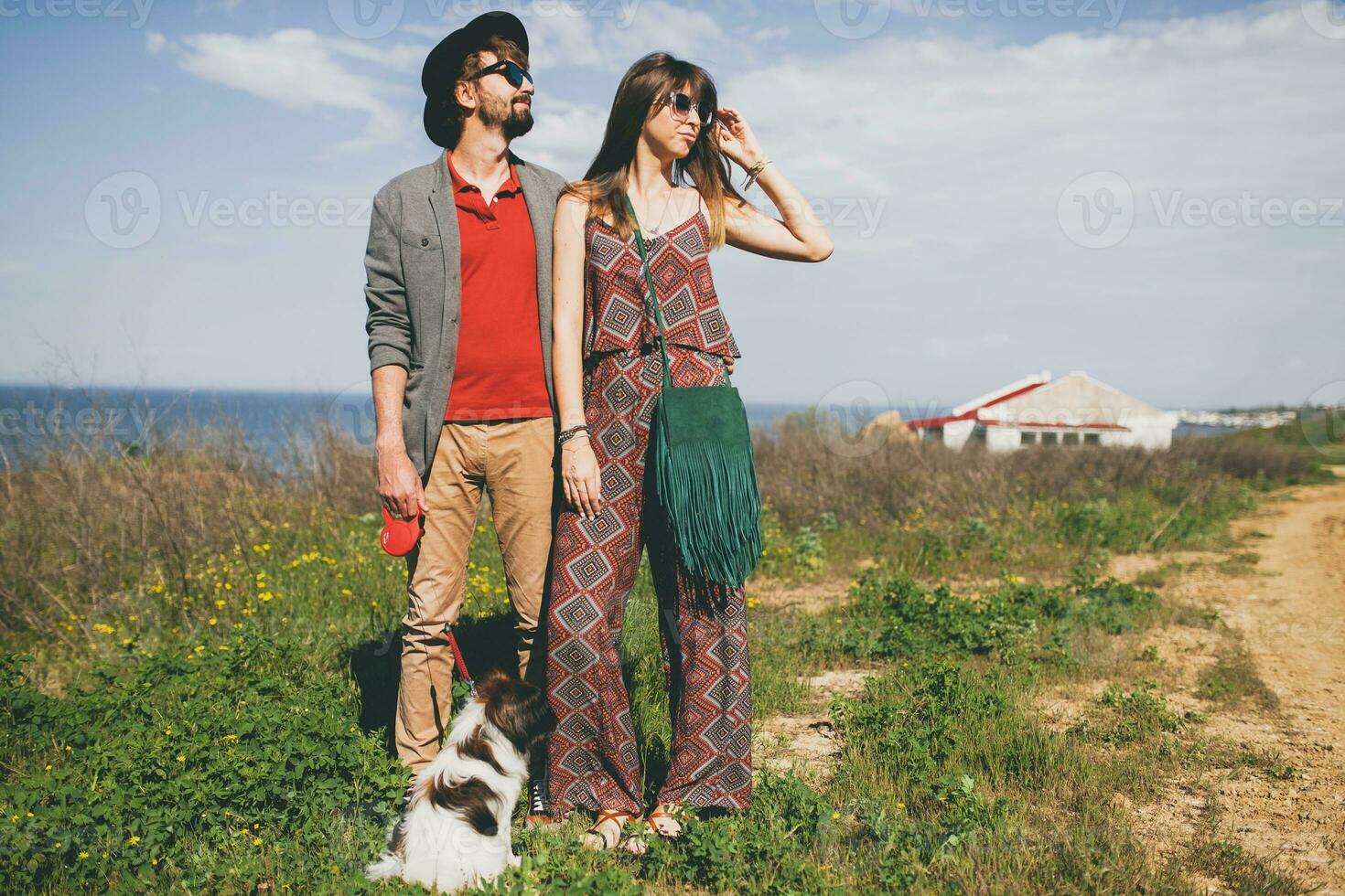 young stylish hipster couple in love walking with dog in countryside photo