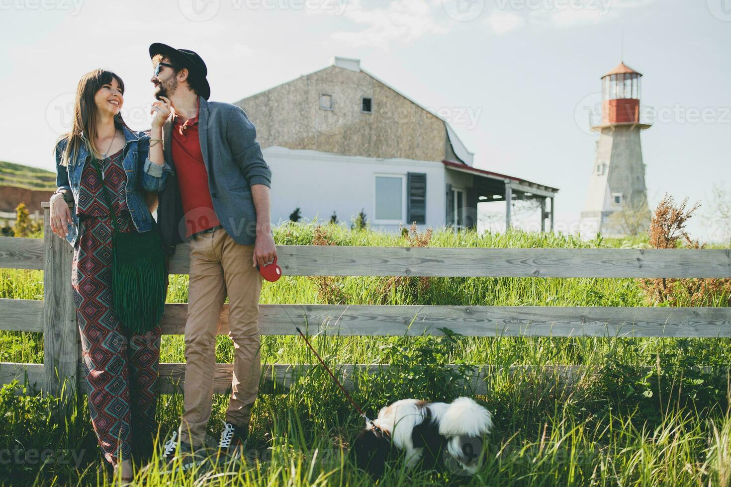 young stylish hipster couple in love walking with dog in countryside photo