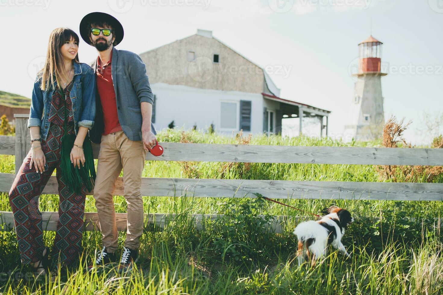 young stylish hipster couple in love walking with dog in countryside photo