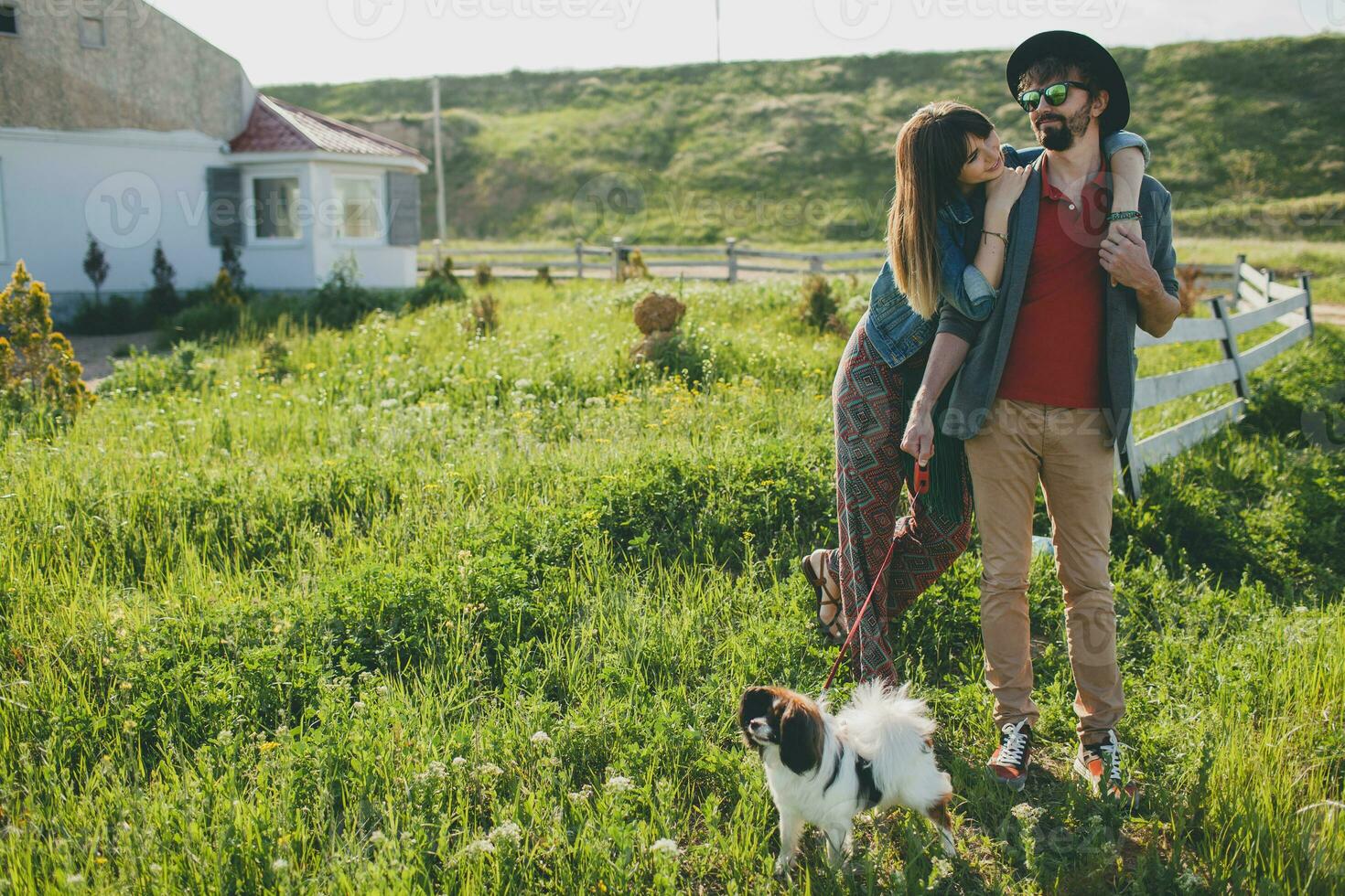 stylish hipster couple in love walking with dog in countryside photo