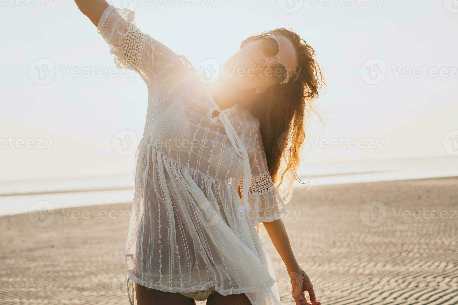 slim beautiful woman in white cotton dress walking on tropical beach photo