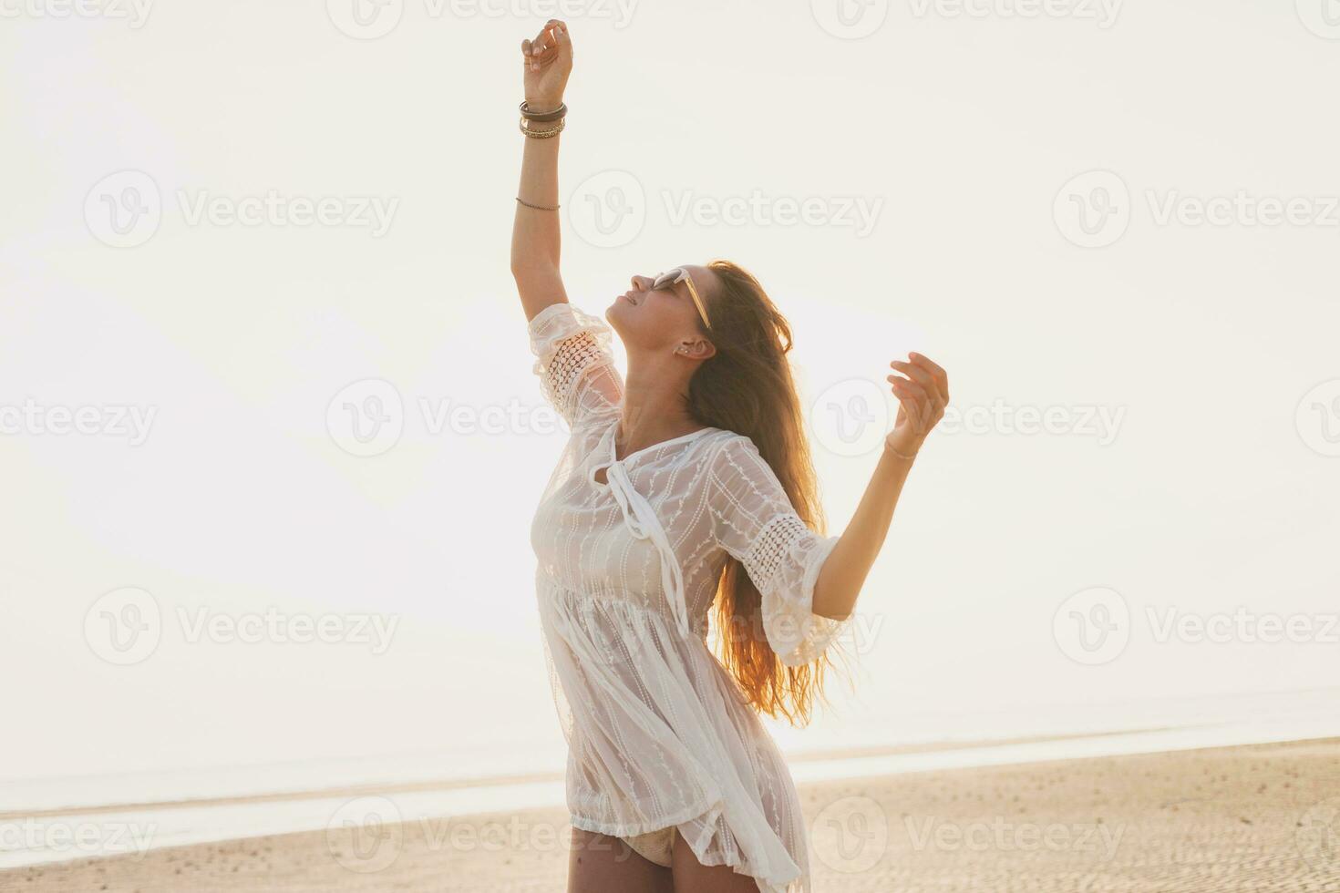 slim beautiful woman in white cotton dress walking on tropical beach photo