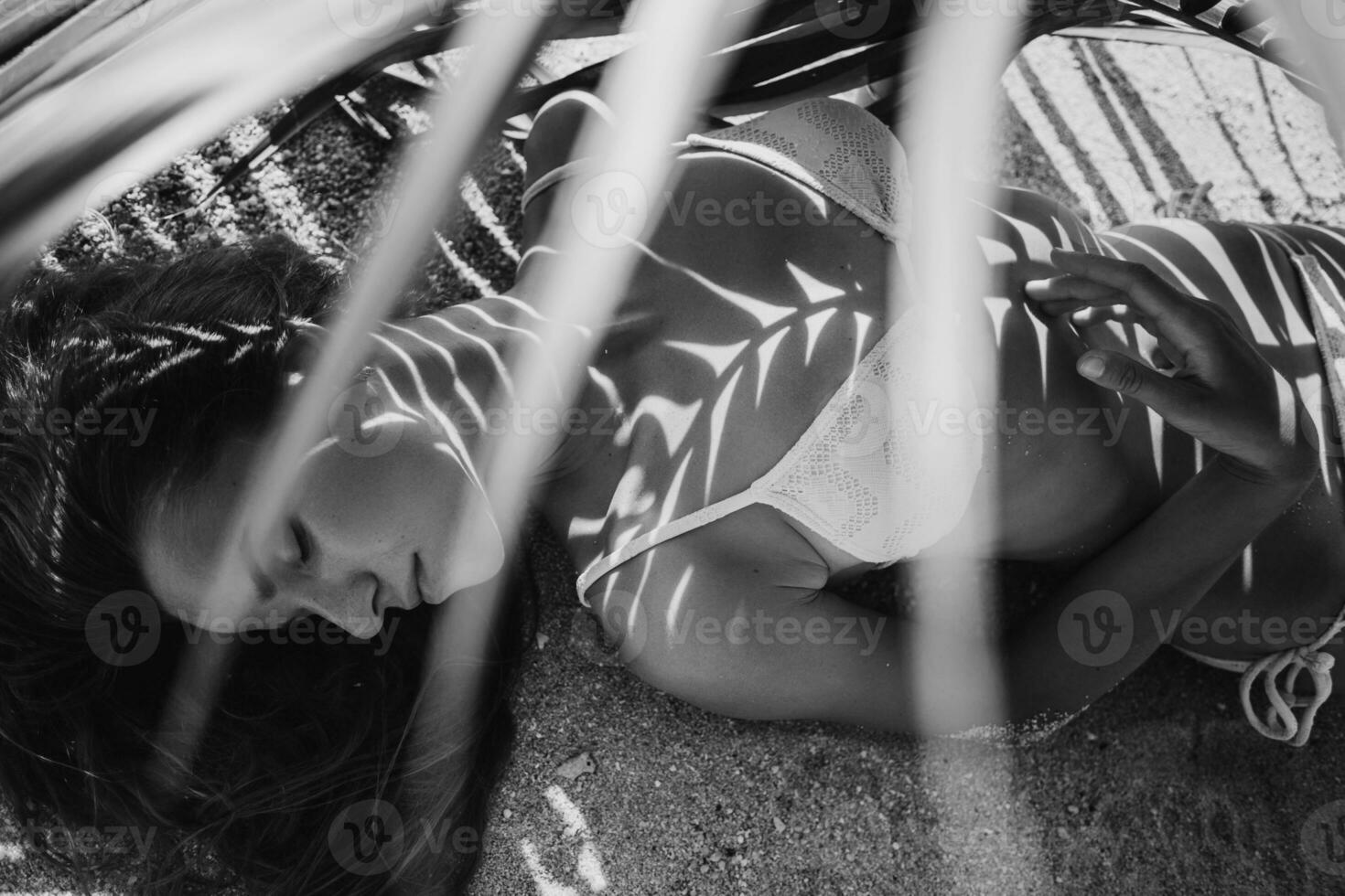 young skinny woman in white bikini swimwear holding leaf of palm tree photo