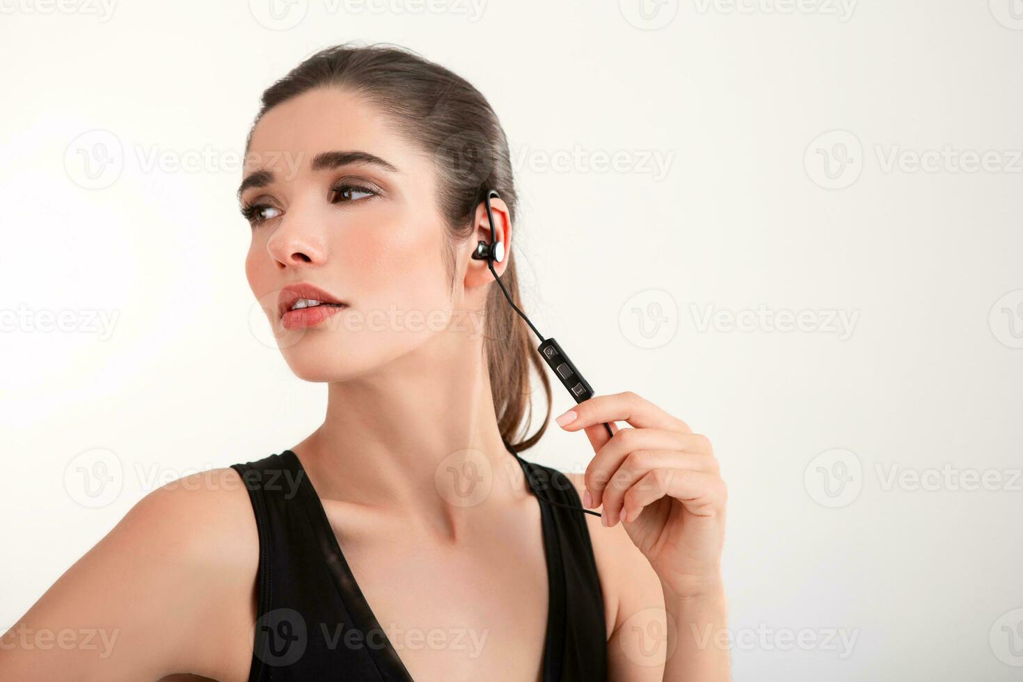 attractive woman in jogging black top listening to music on earphones photo