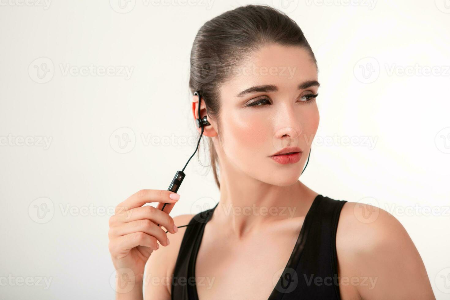 attractive woman in jogging black top listening to music on earphones photo