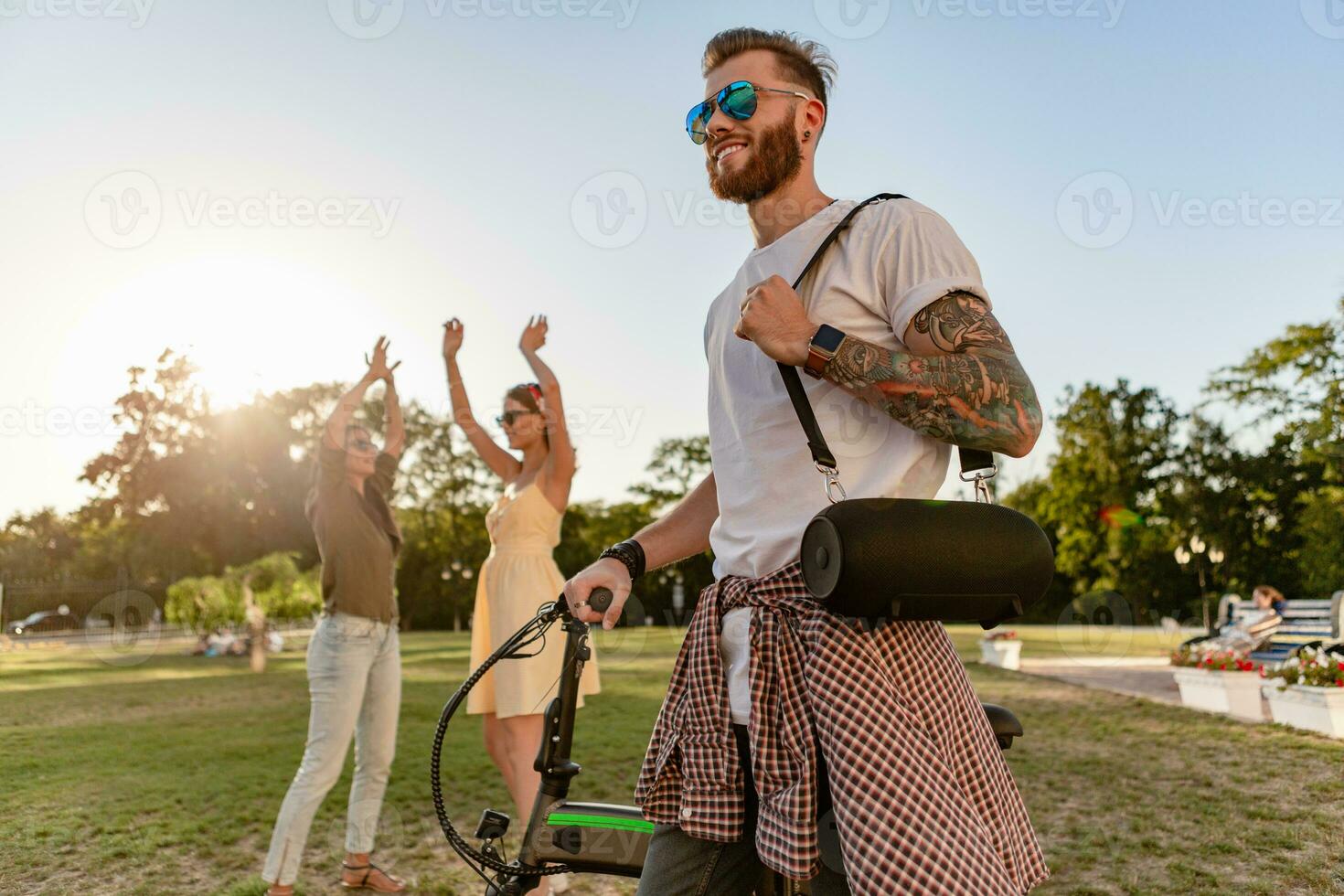 company of friends having fun together in park listening to music photo