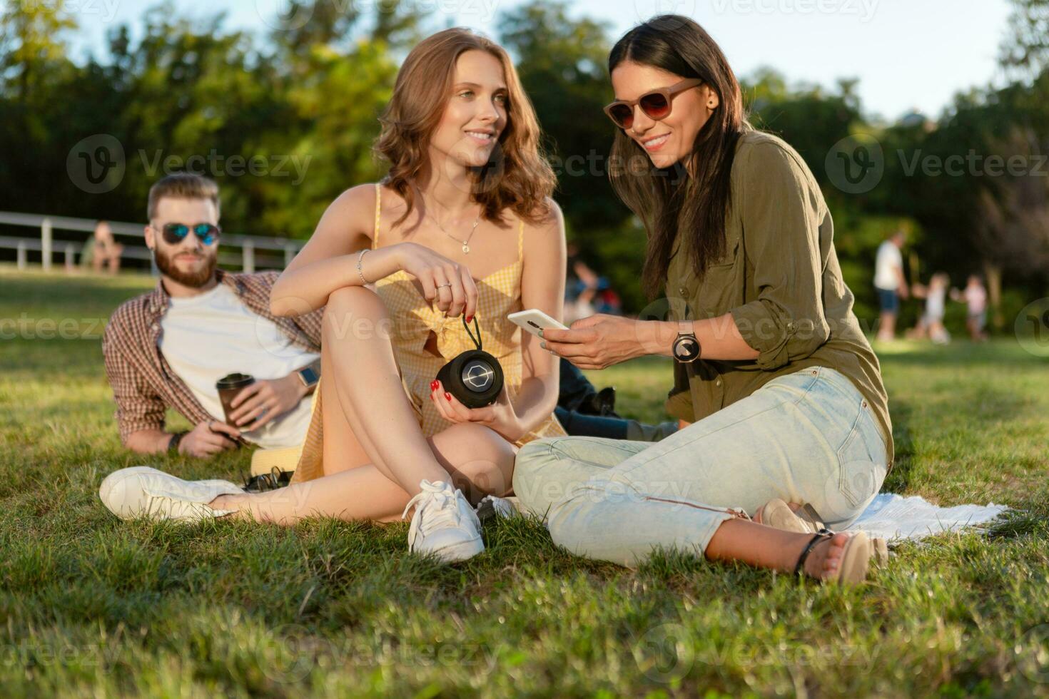 company of friends having fun together in park listening to music photo