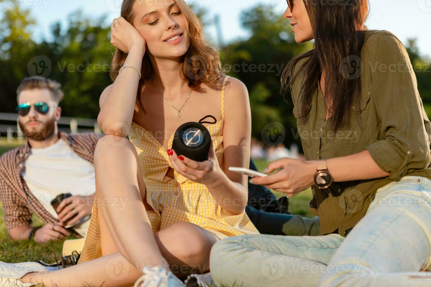 company of friends having fun together in park listening to music photo