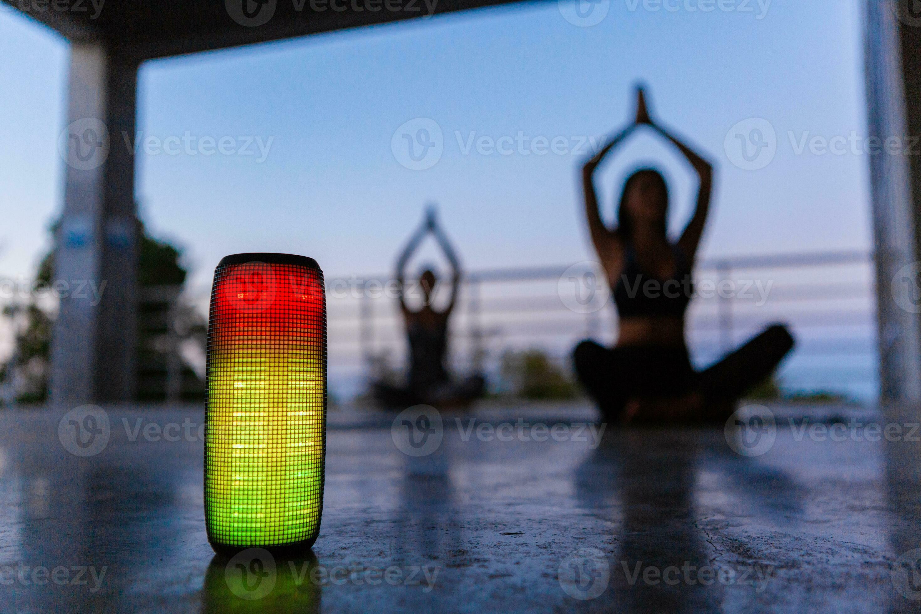 wireless speaker on foreground of company of friends doing yoga