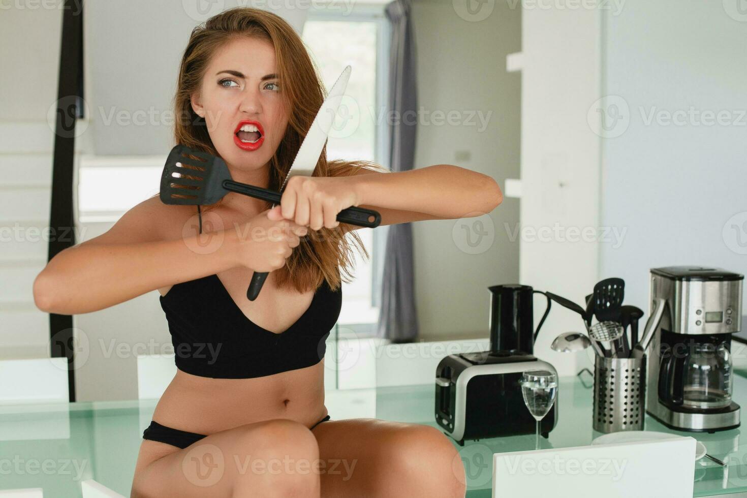 young slim beautiful woman sitting on kitchen table holding knife, sexy, black underwear, housewife, sensual, dinning room, household appliances, skinny body, tanned skin photo