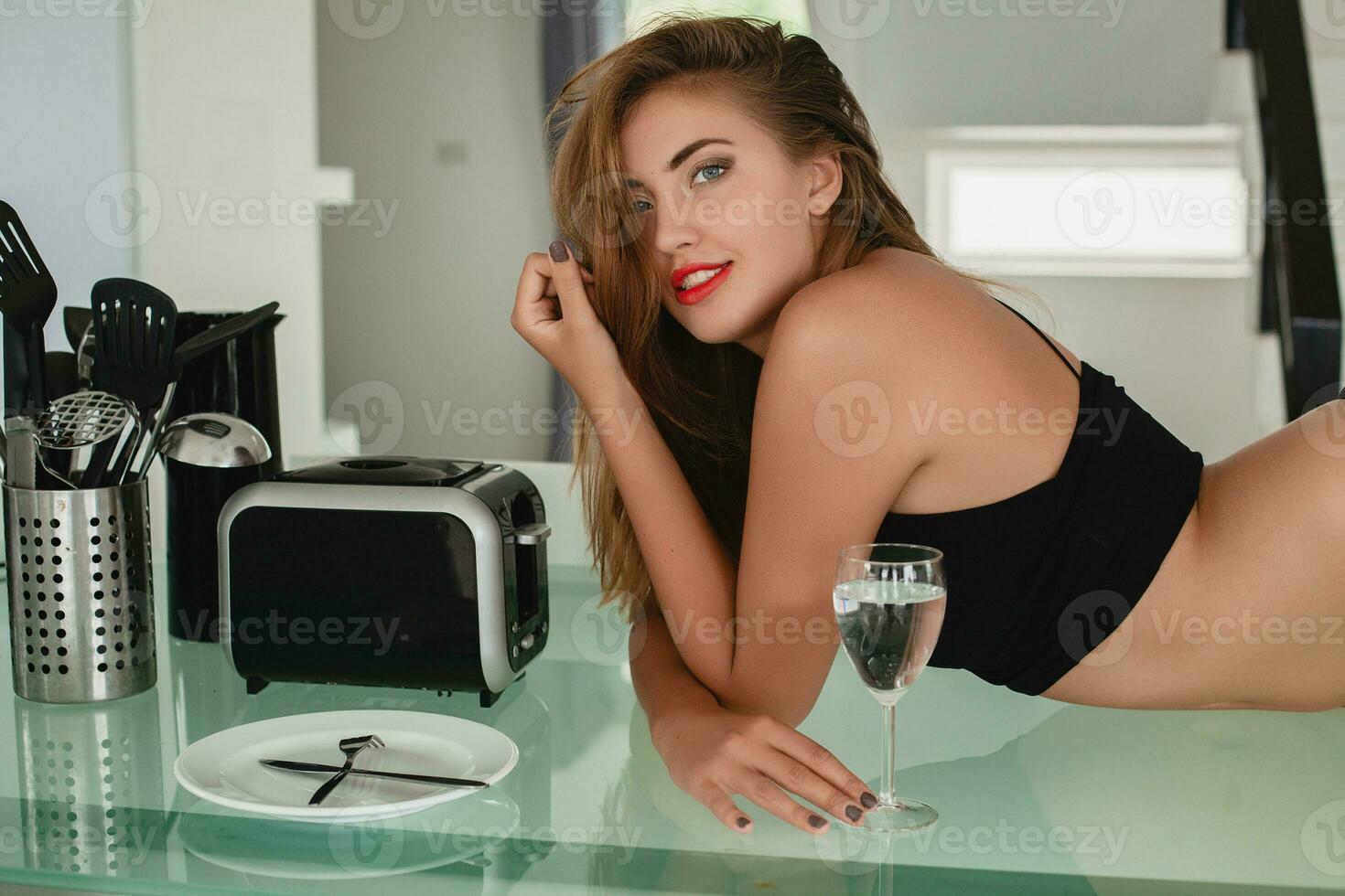 young slim beautiful woman lying on kitchen table sexy, black underwear, housewife, sensual, dinning room, household appliances, skinny body, tanned skin photo