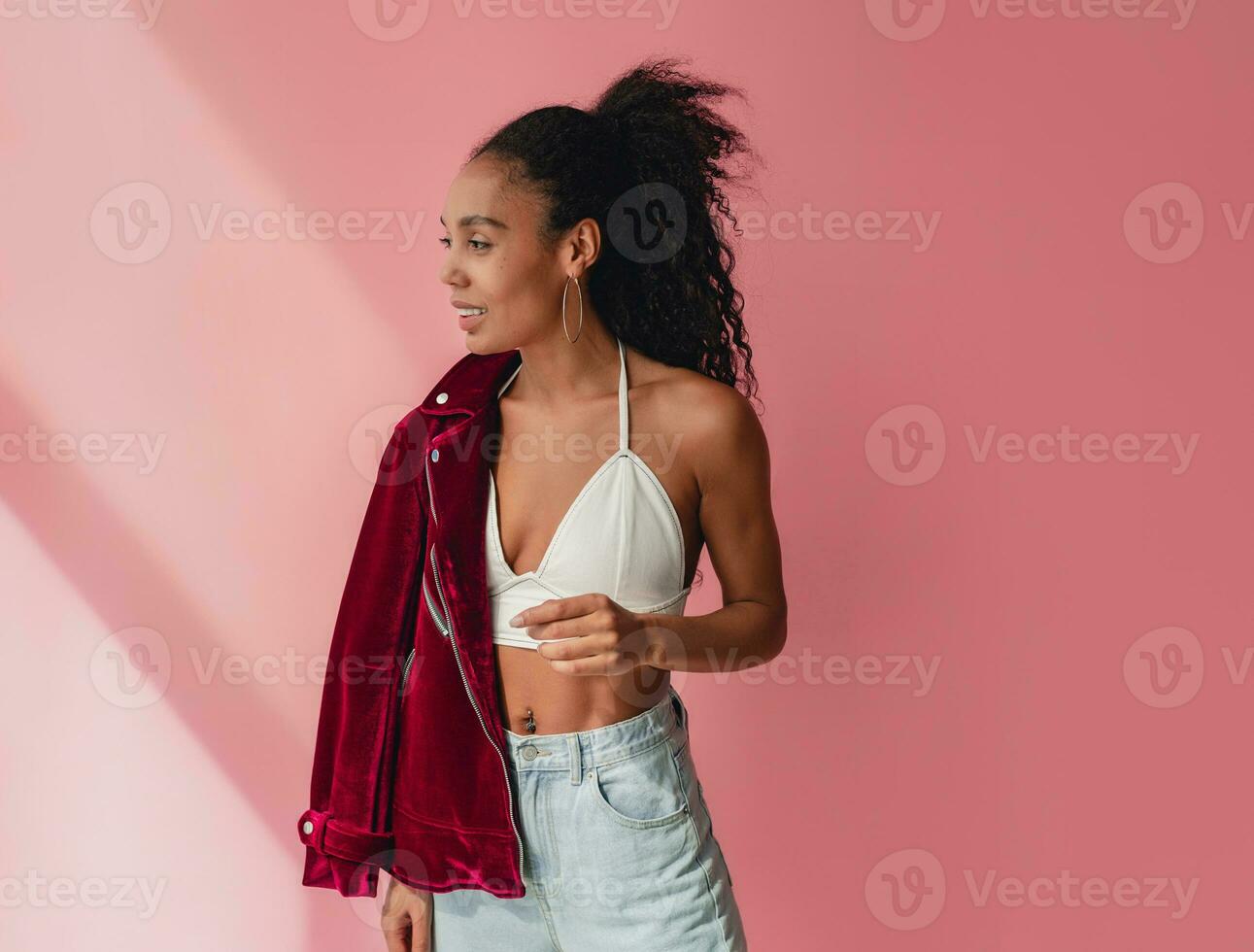 attractive black african american woman in stylish outfit on pink background photo