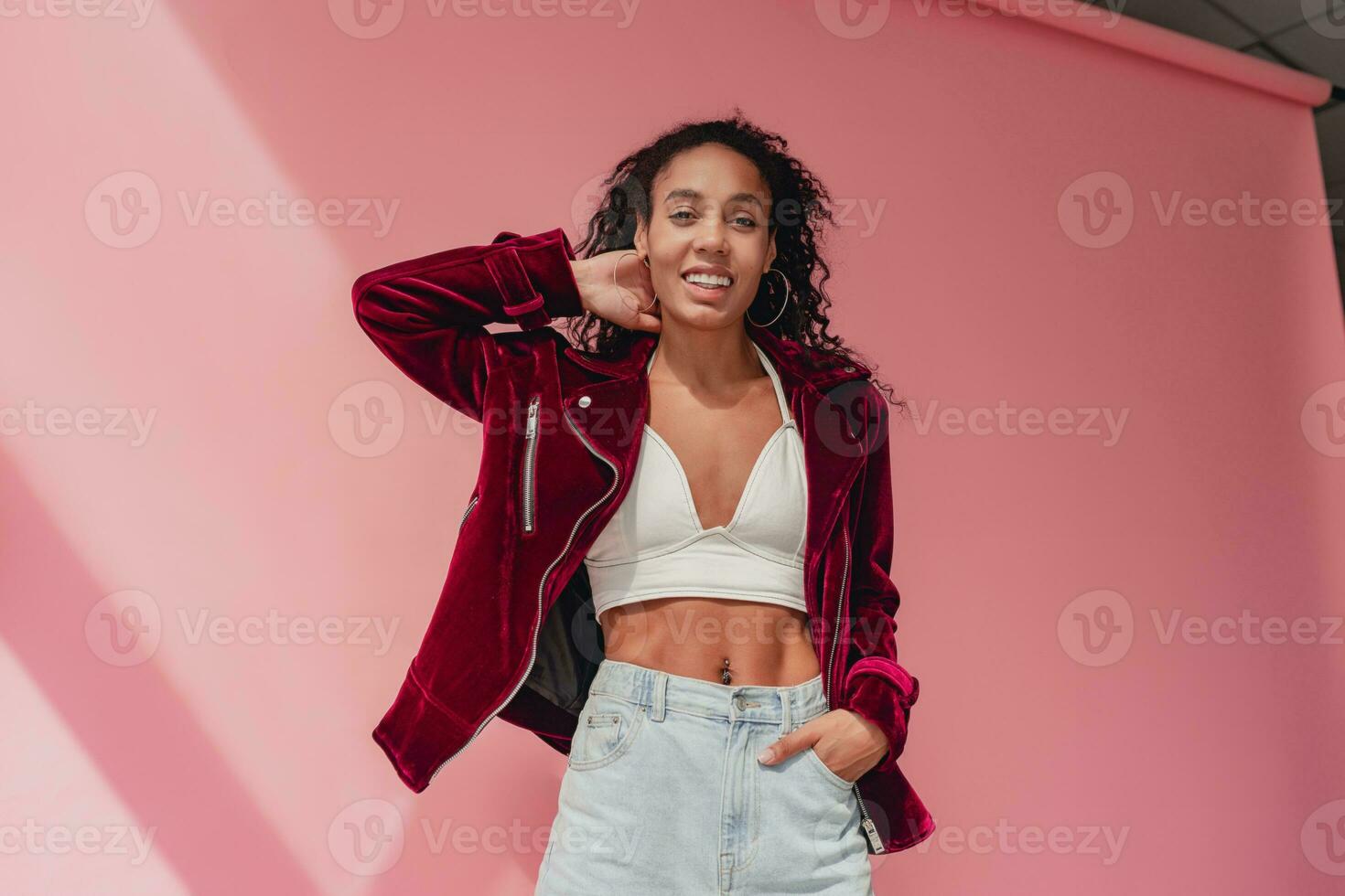 attractive black african american woman in stylish outfit on pink background photo