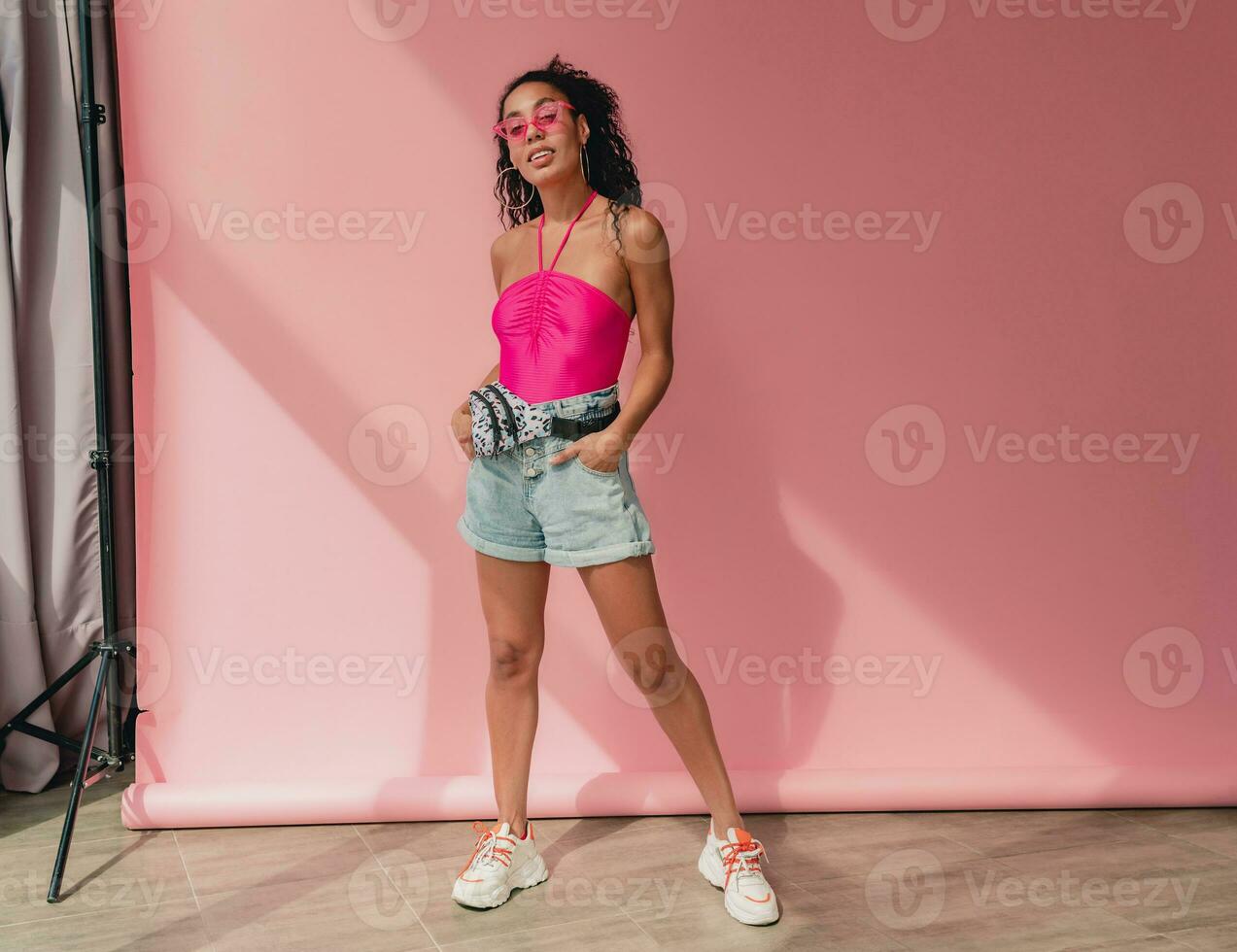 attractive black african american woman in stylish outfit on pink background photo
