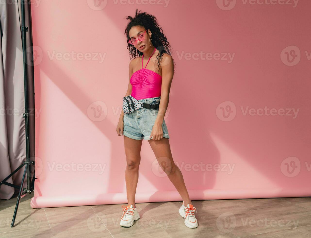 attractive black african american woman in stylish outfit on pink background photo