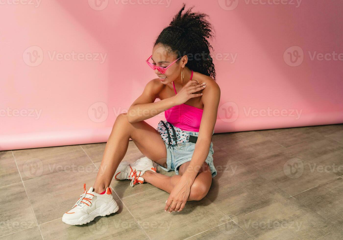 attractive black african american woman in stylish outfit on pink background photo