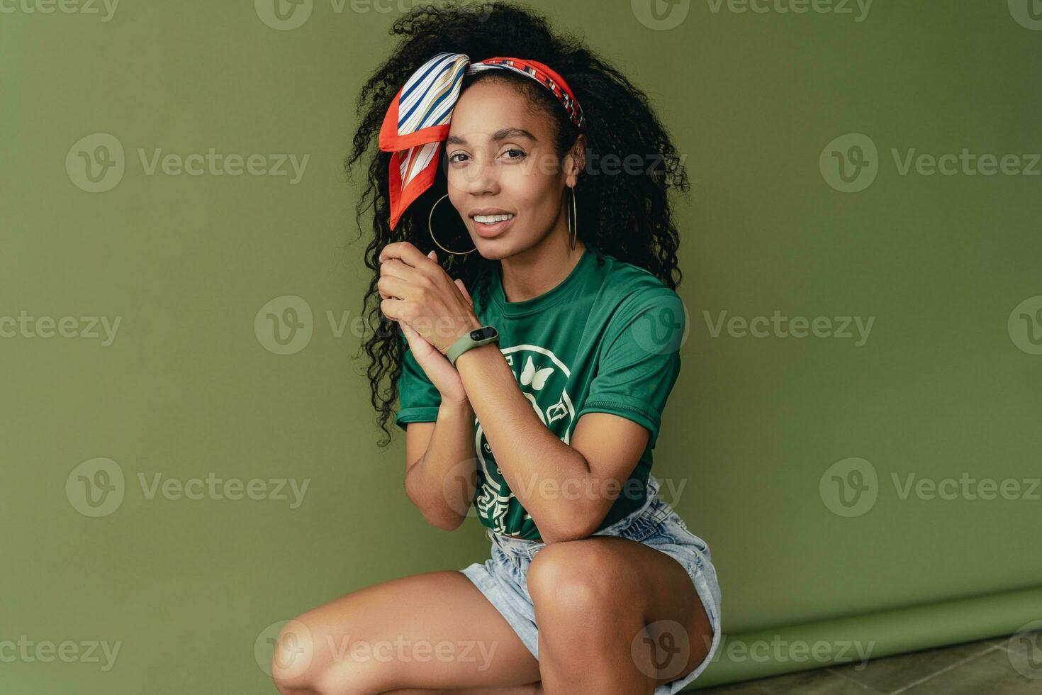 attractive black african american woman posing in stylish hipster outfit on green background photo