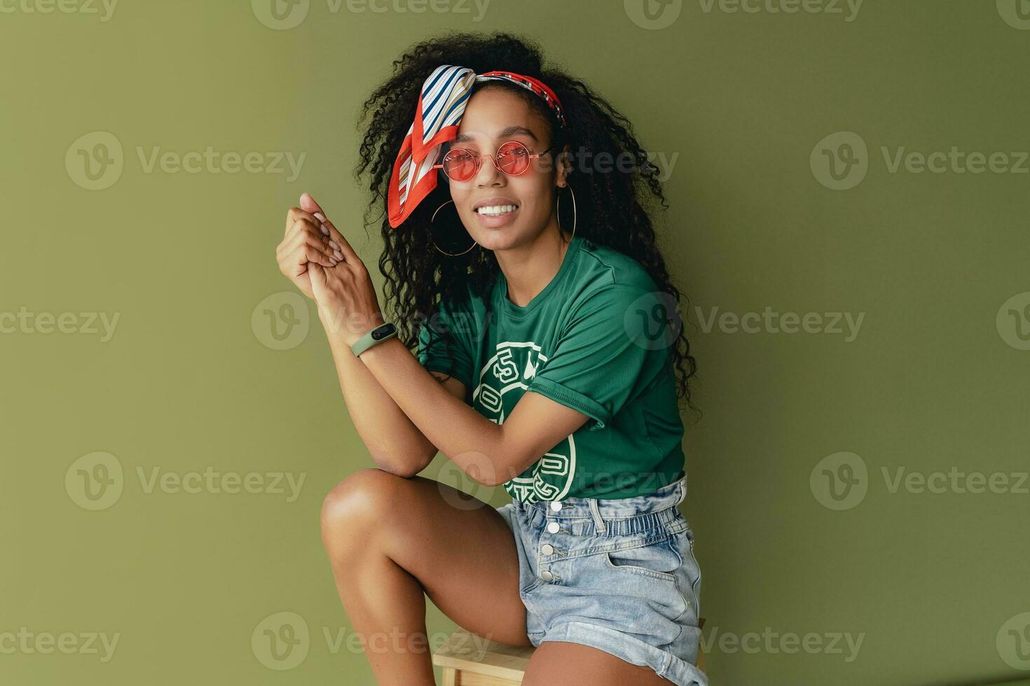 attractive black african american woman posing in stylish hipster outfit on green background photo