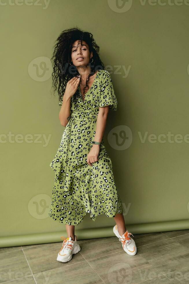 attractive black african american woman posing in stylish green dress isolated on green background photo