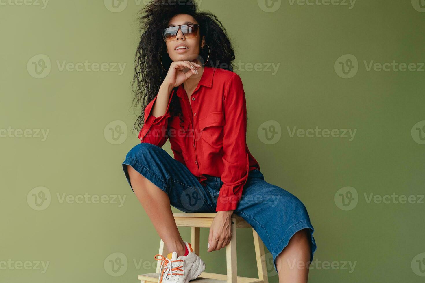 attractive black african american woman in stylish outfit on green studio background photo