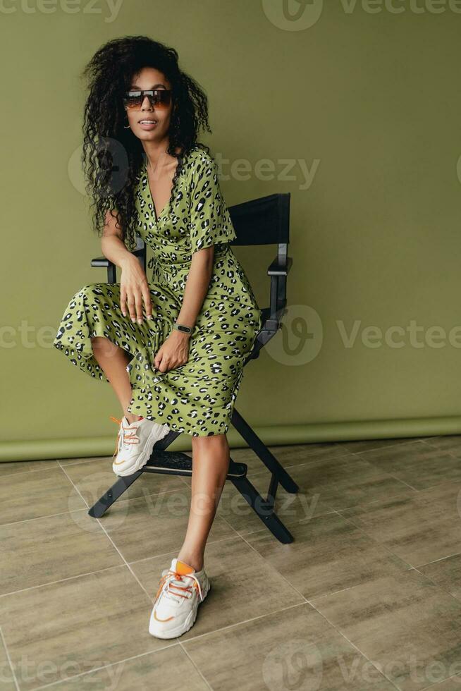 attractive black african american woman posing in stylish green dress isolated on green background photo