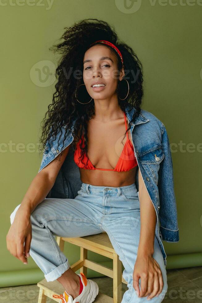 attractive black african american woman posing in stylish hipster outfit on green background photo