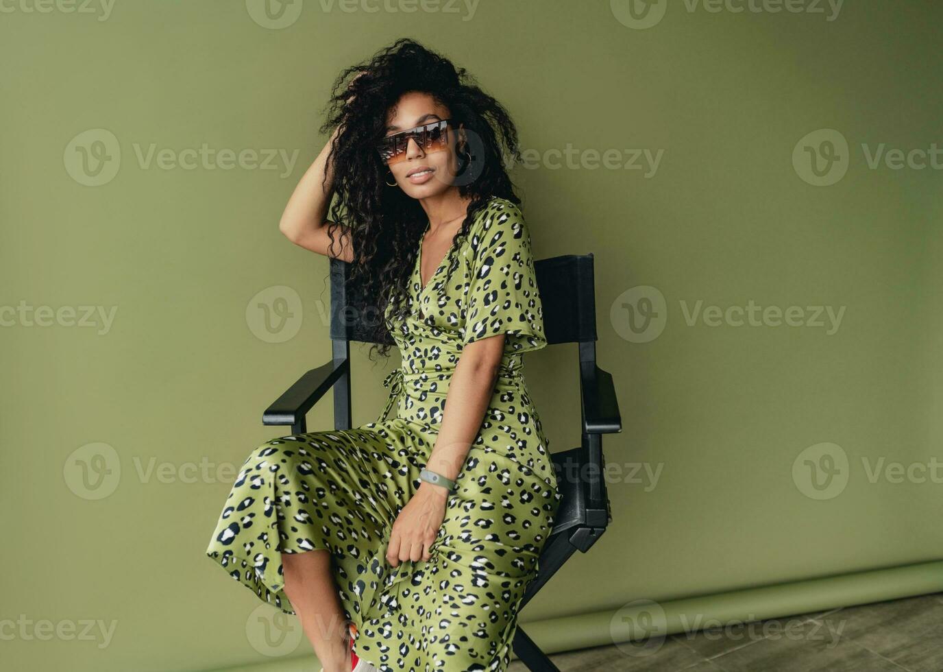 attractive black african american woman posing in stylish green dress isolated on green background photo