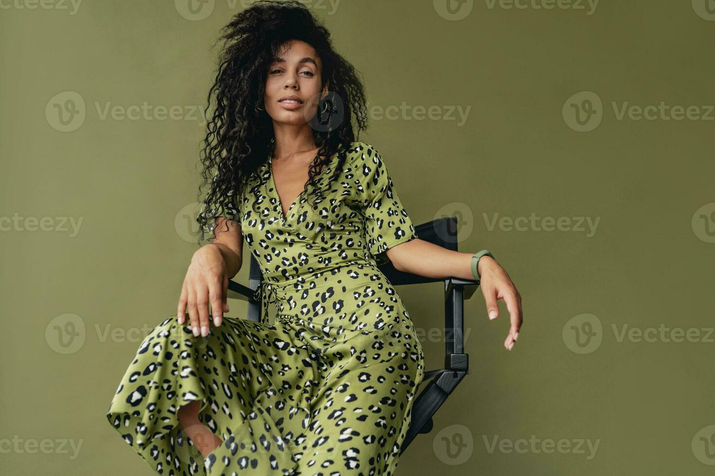 attractive black african american woman posing in stylish green dress isolated on green background photo