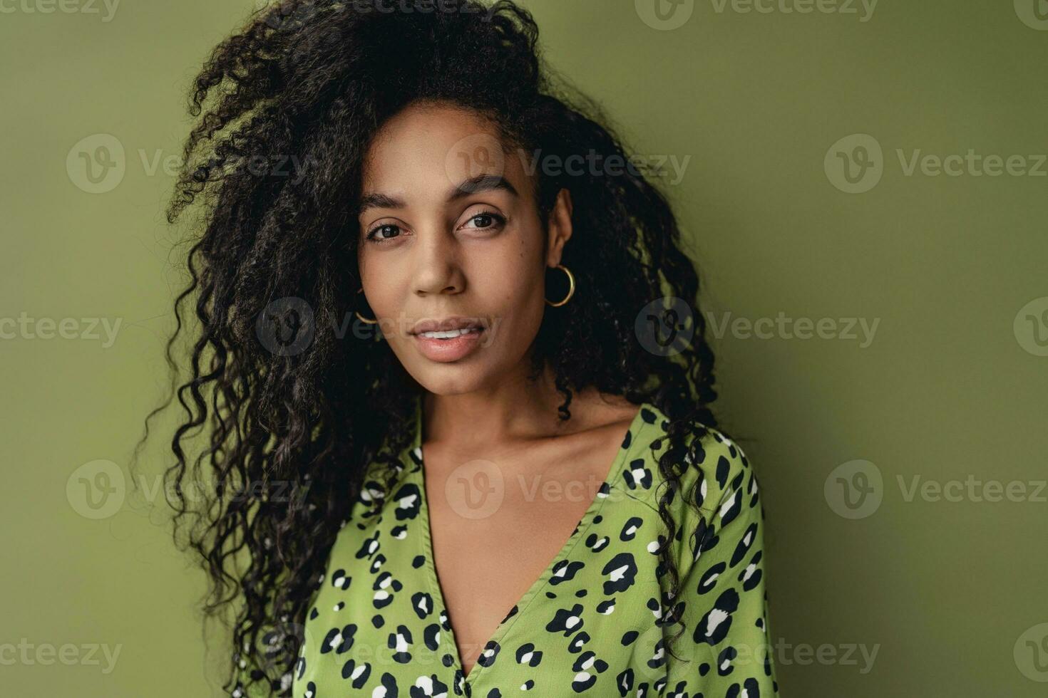 attractive black african american woman posing in stylish green dress isolated on green background photo