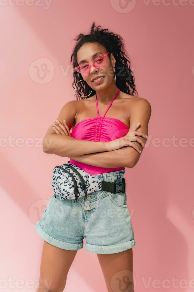 attractive black african american woman in stylish outfit on pink background photo