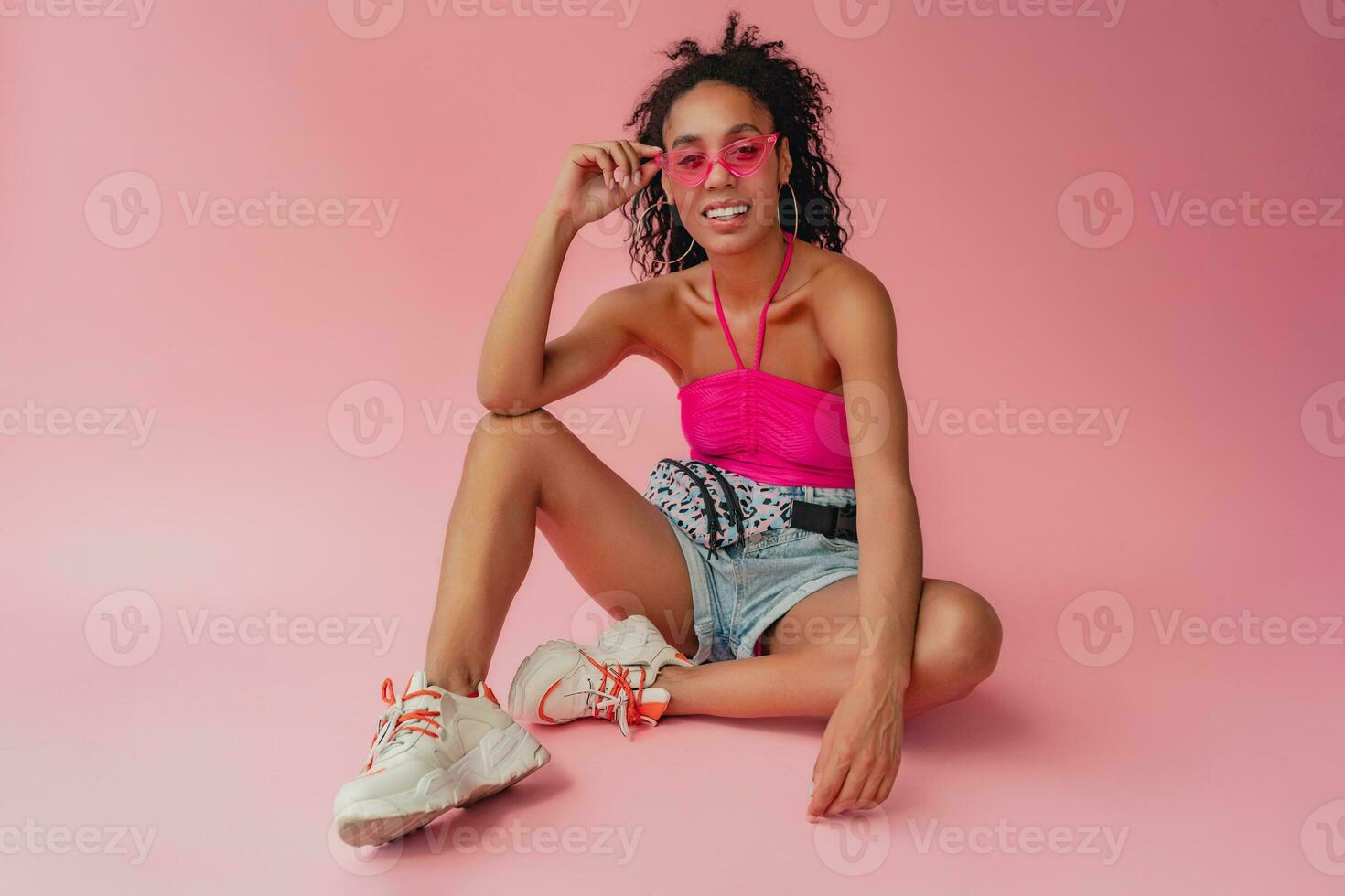 attractive black african american woman in stylish outfit on pink background photo