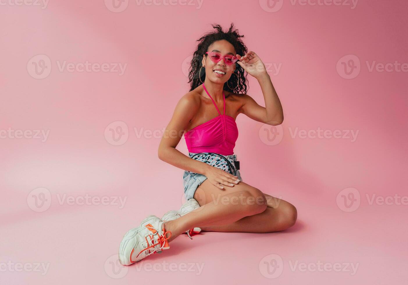 attractive black african american woman in stylish outfit on pink background photo