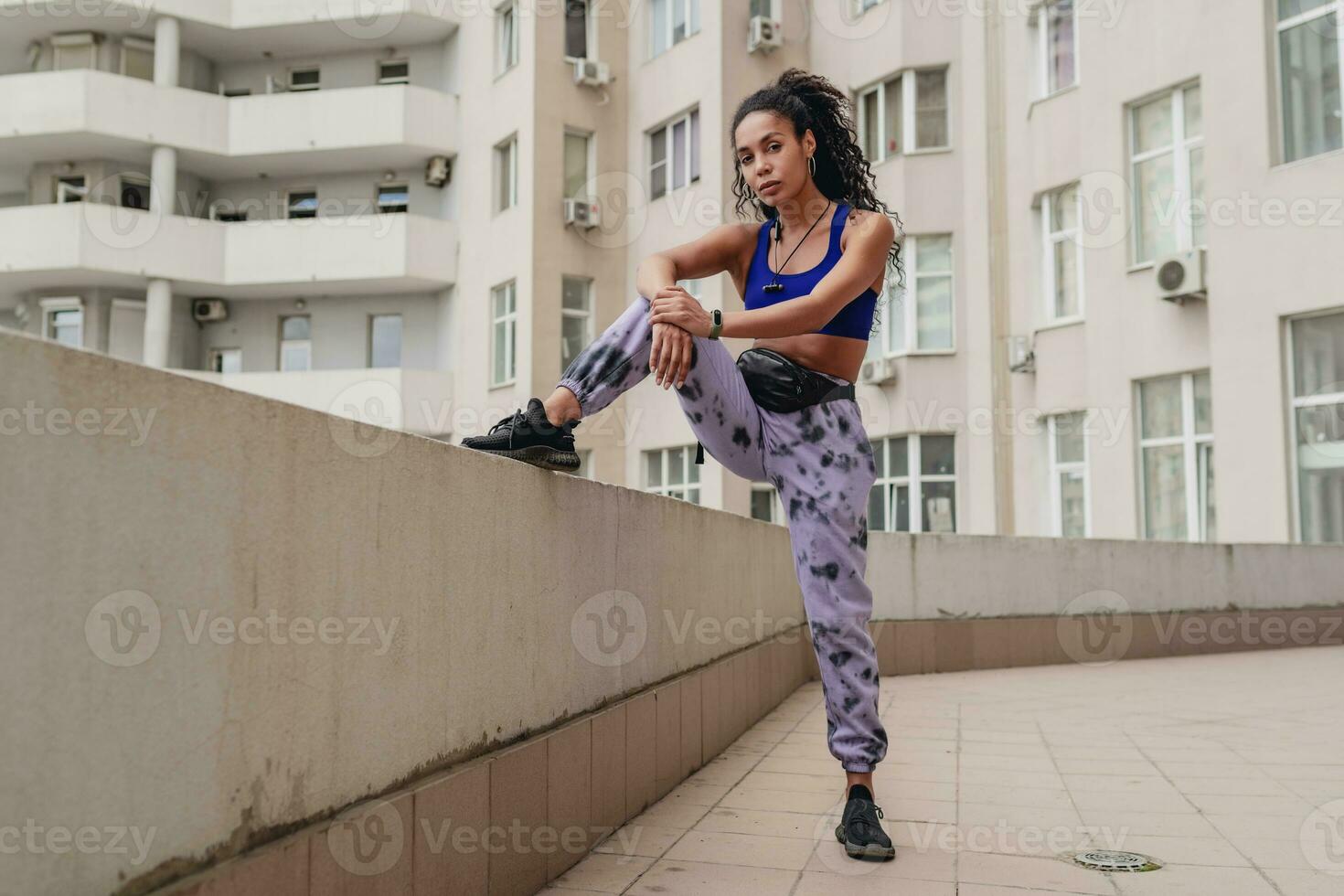 attractive black african american woman in sport fitness outfit on rooftop making work out photo